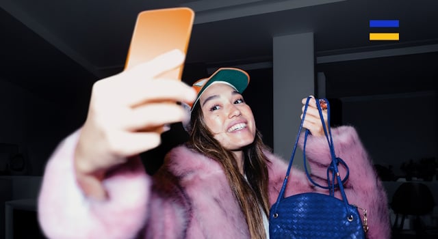 Lady takes a selfie holding up a handbag