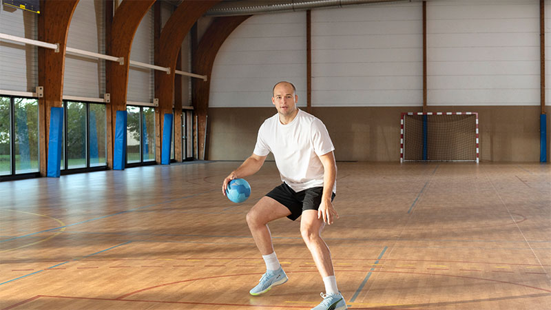 Paul Drux in einer Turnhalle beim Spiel mit einem Handball